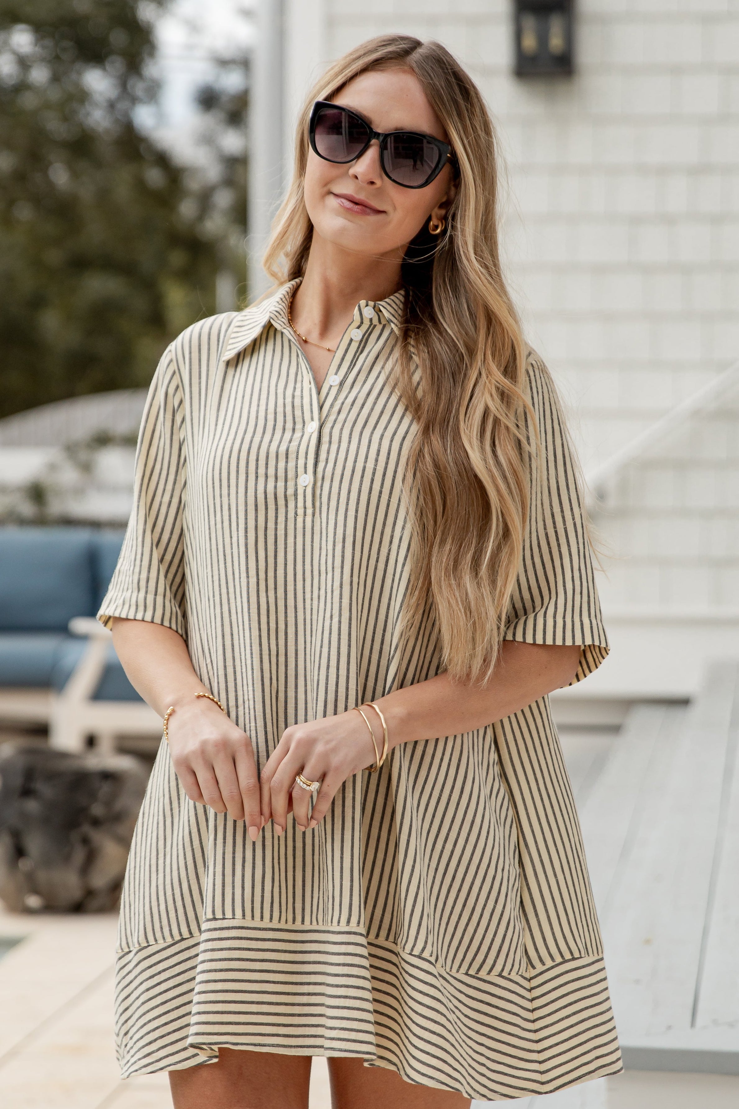 Woman wearing a striped dress and sunglasses outdoors.