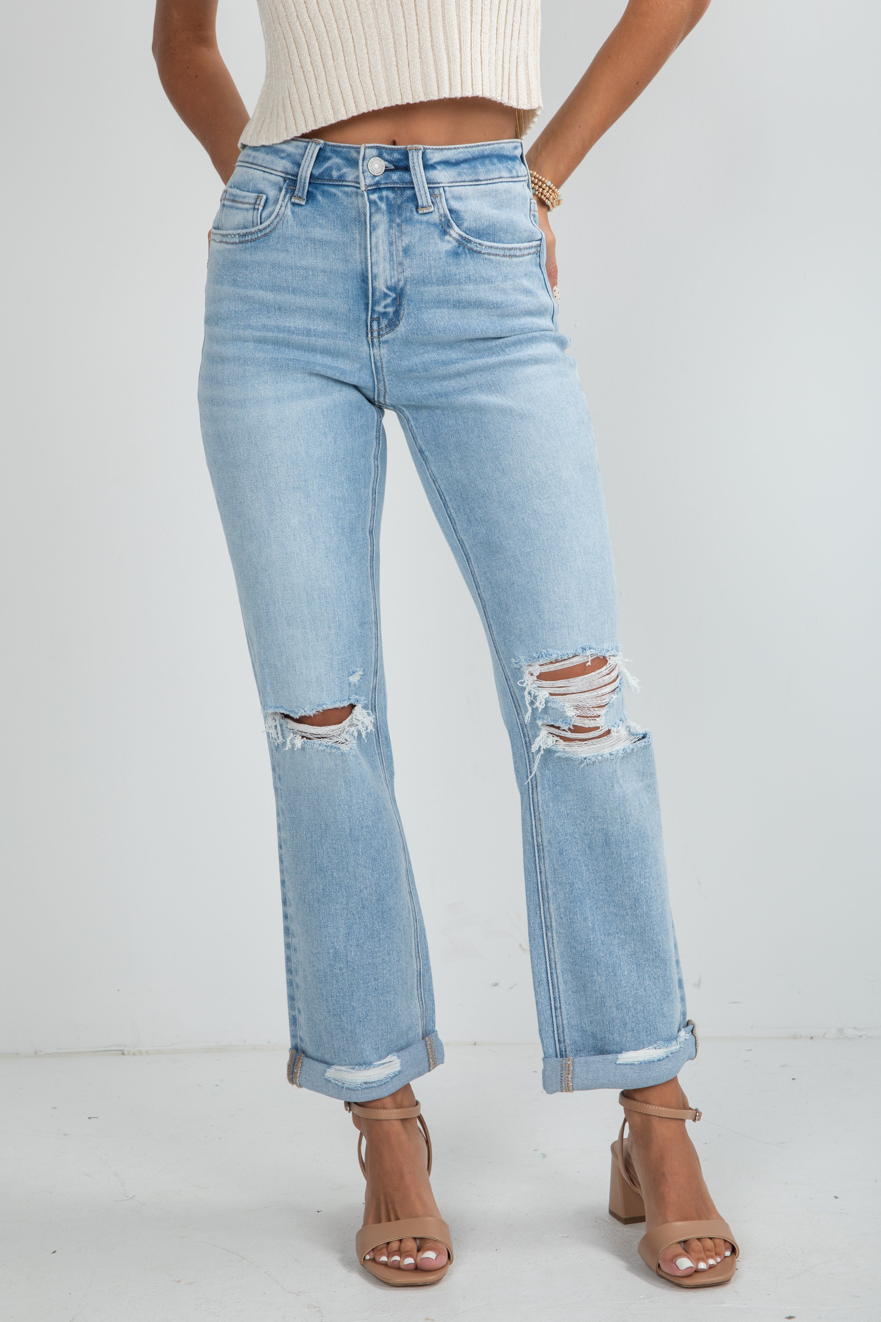 Person wearing light blue distressed jeans on a white background