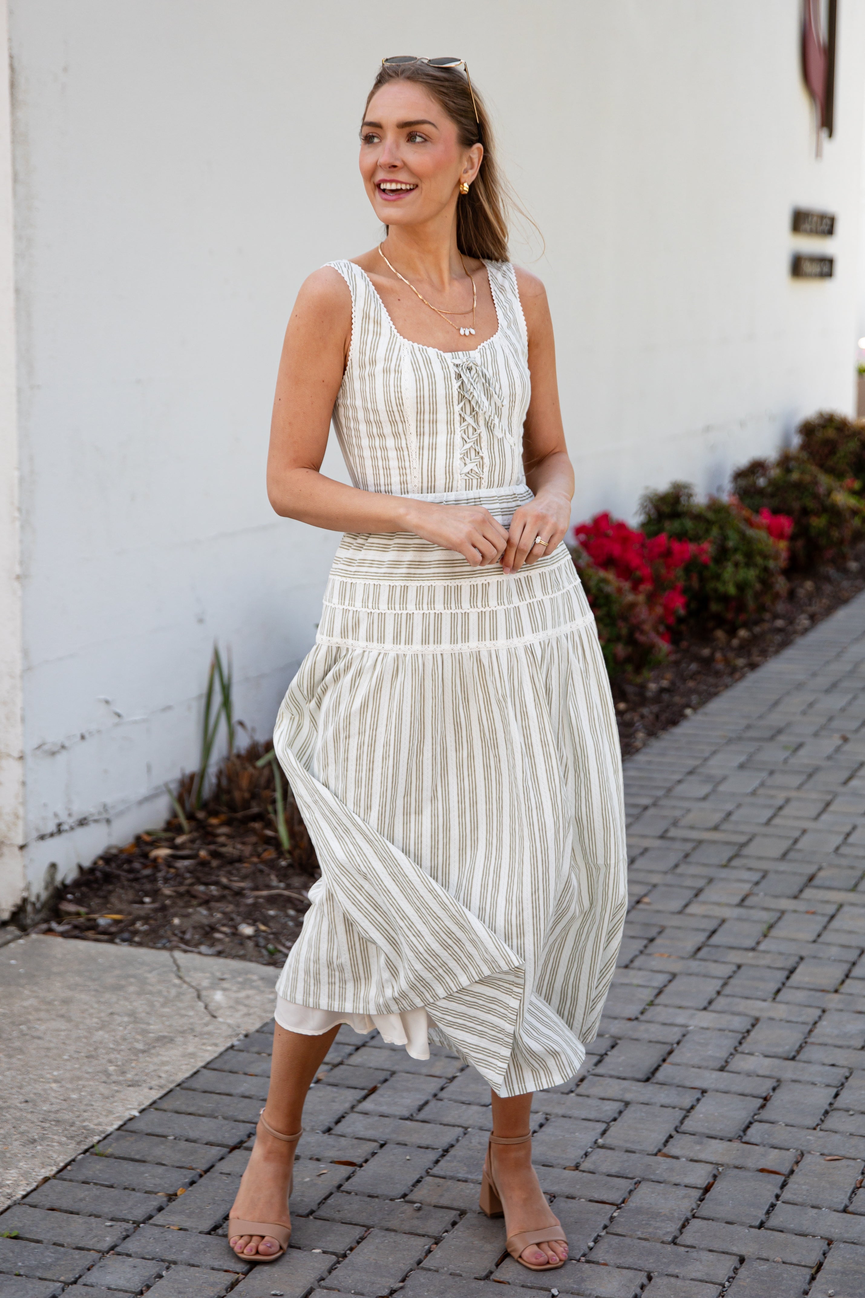 Woman wearing a spring striped maxi dress with sunglasses and nude heels