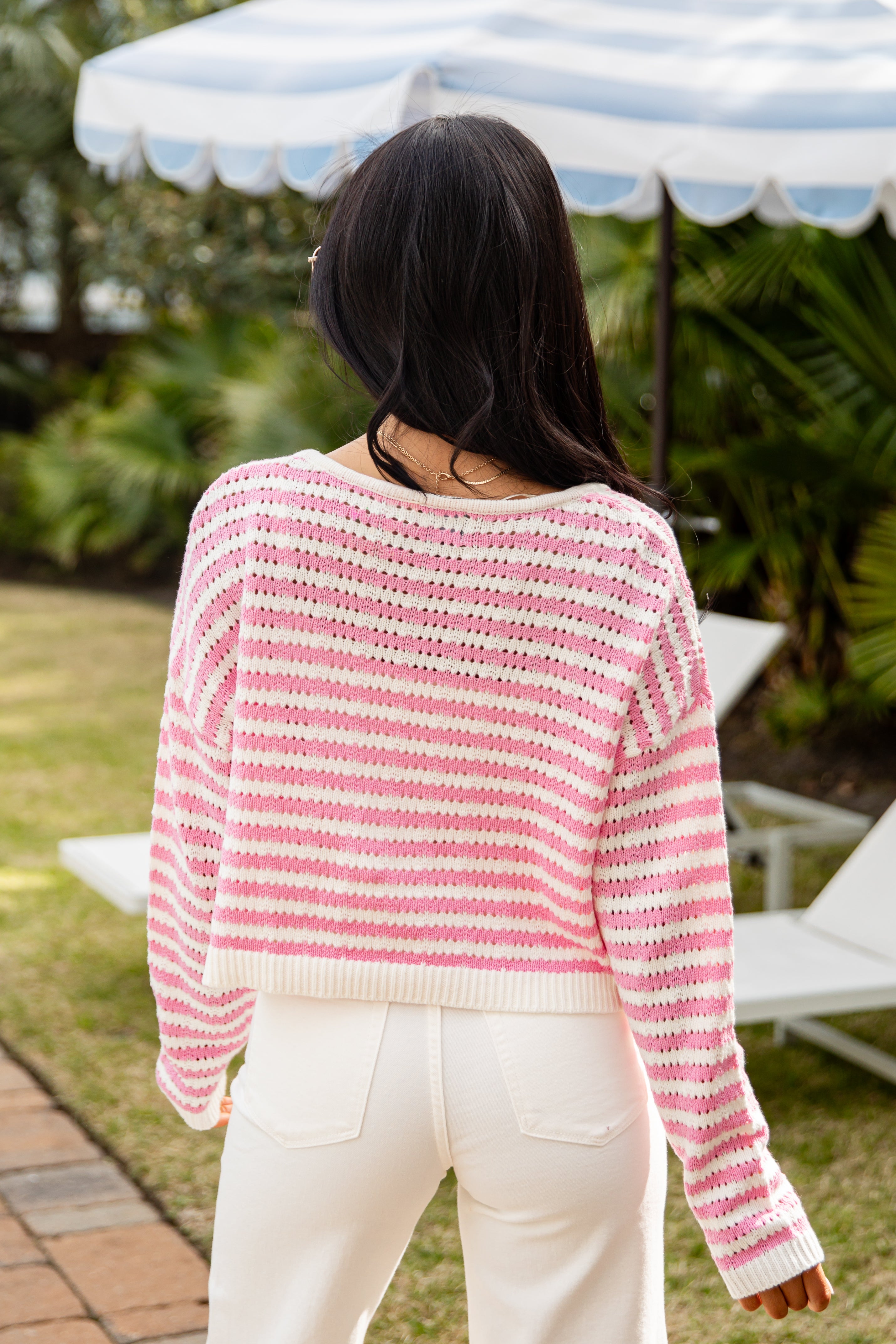 Person wearing a pink and white striped sweater in an outdoor setting