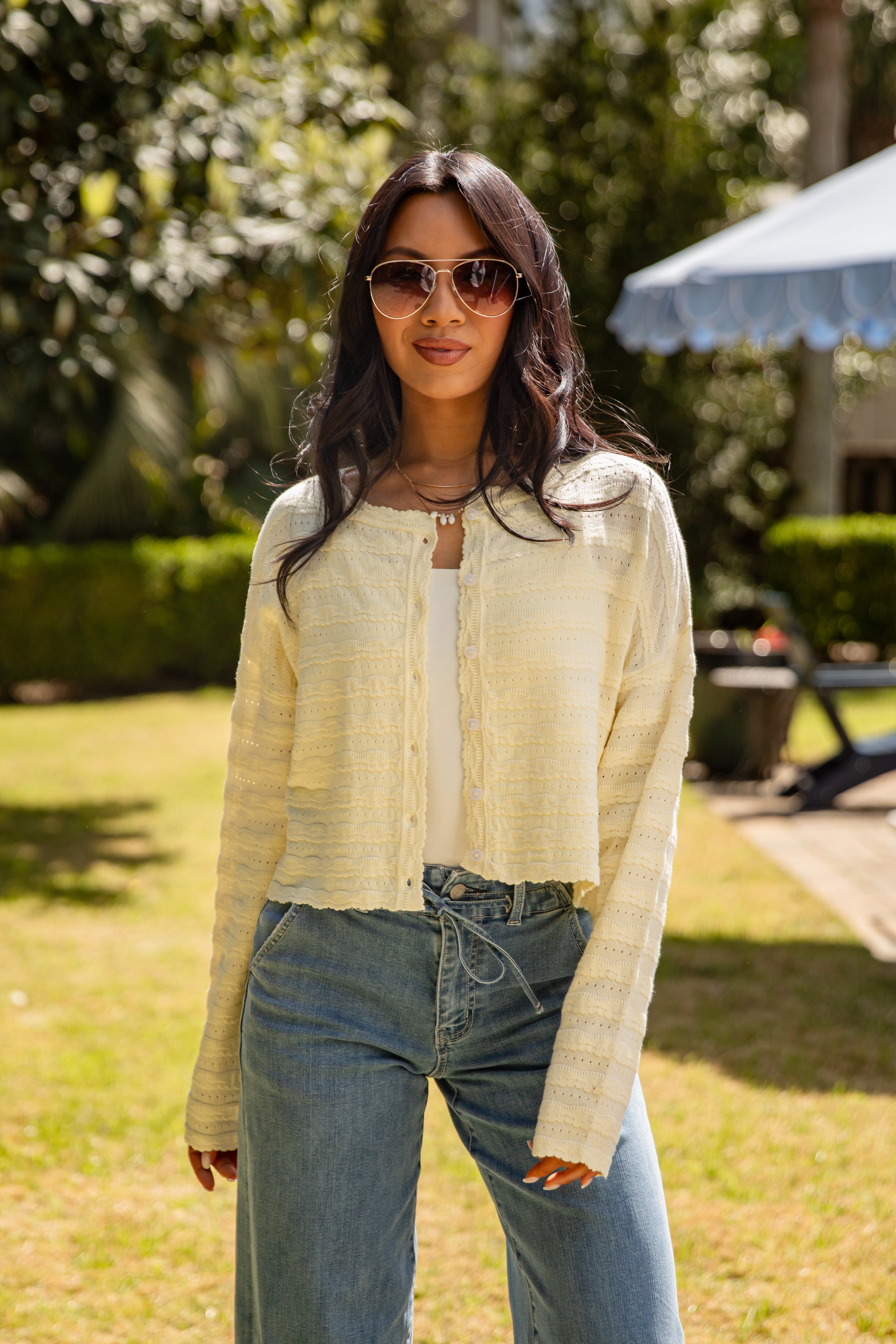 Woman wearing sunglasses and a light-colored jacket outdoors