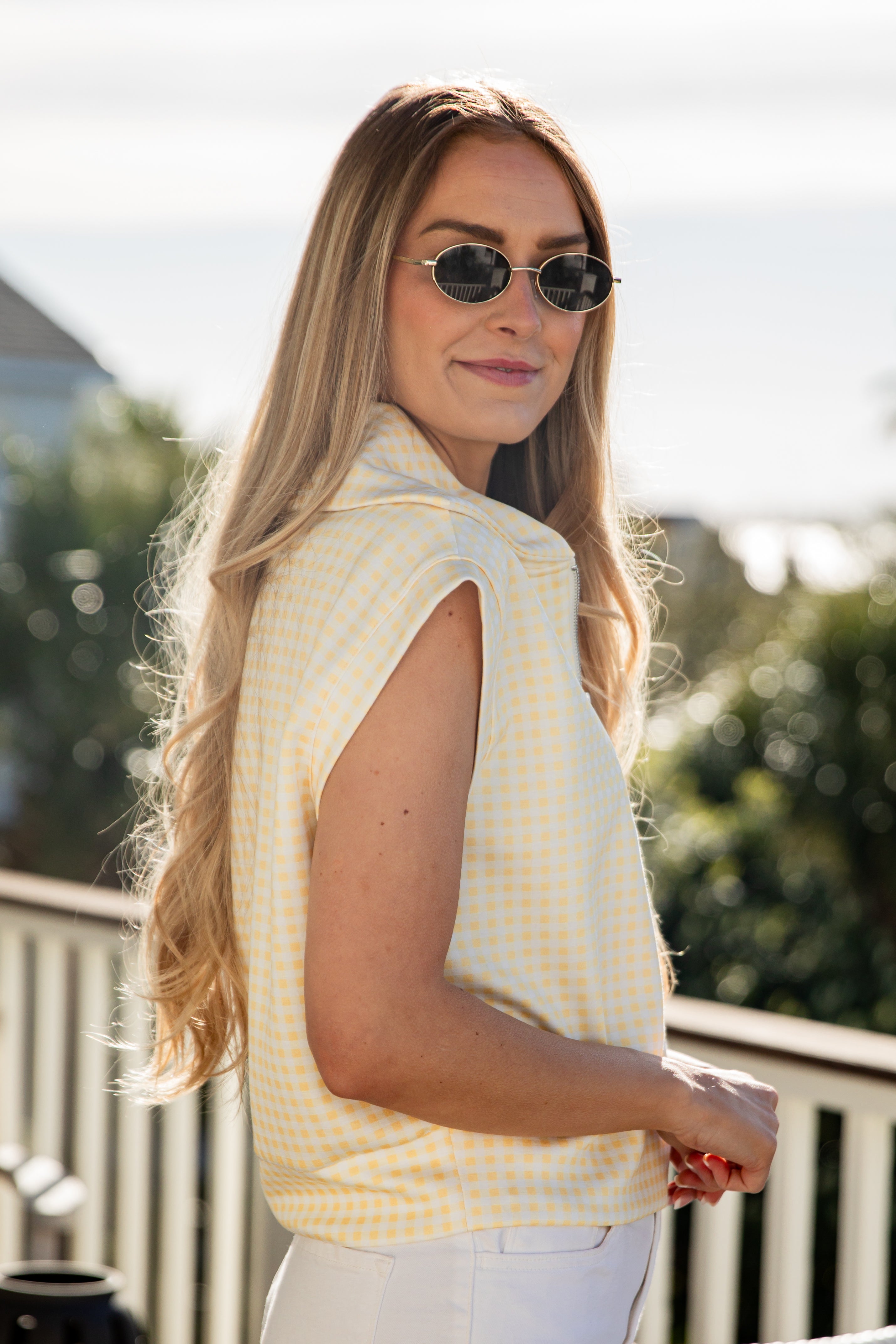 woman wearing a pink gingham quarter zip collared tank top
