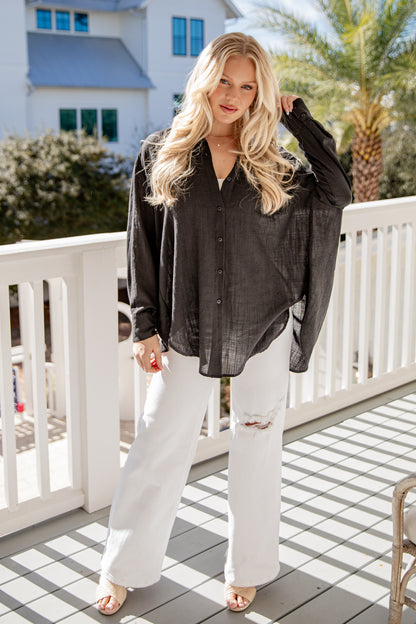 Woman wearing a black shirt and white pants on a balcony