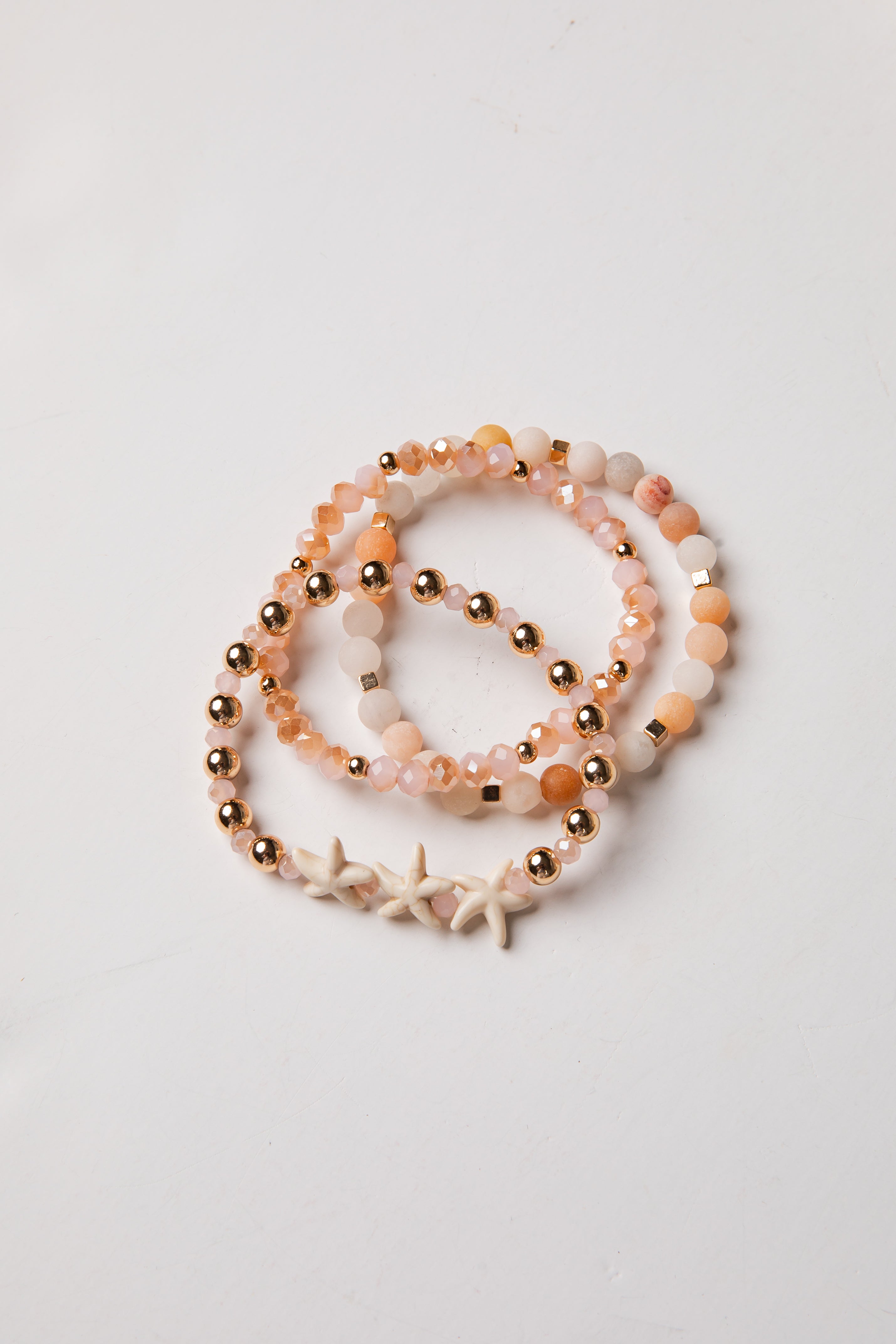 Set of beaded bracelets with starfish charm on a light gray background