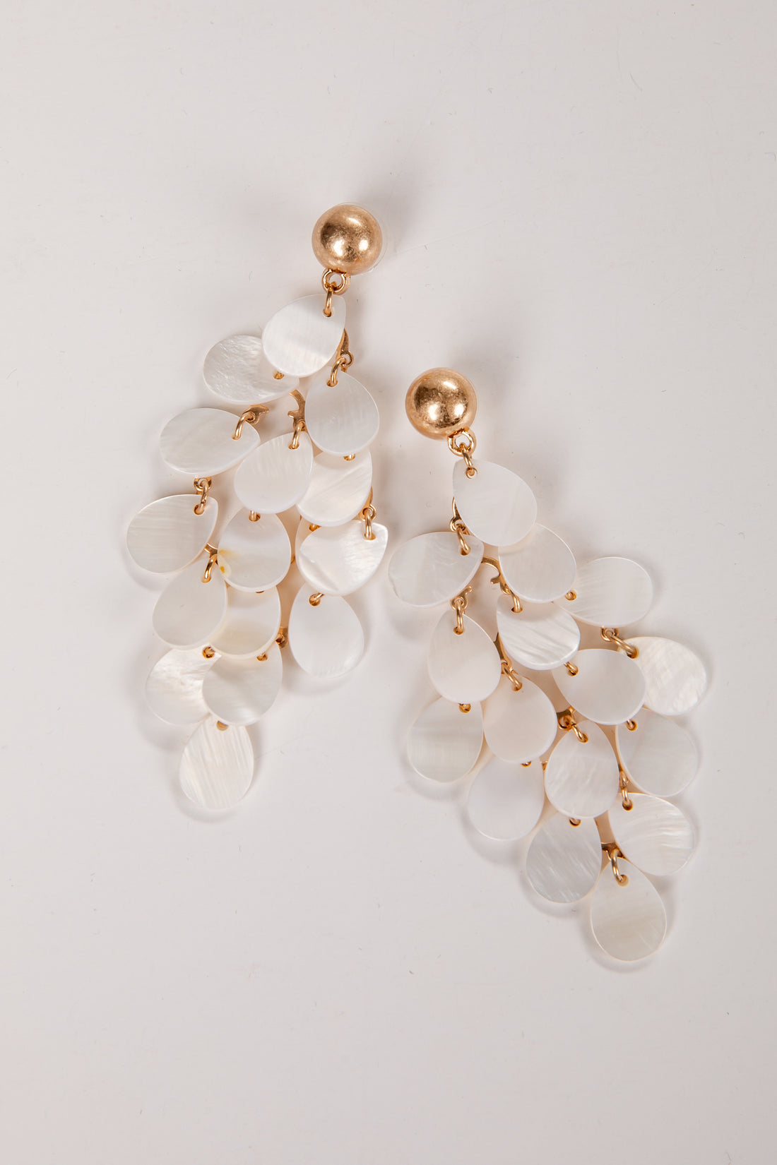 Elegant earrings with white stones and gold accents on a light gray background