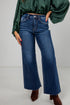 Person wearing blue flared jeans and a green top on a white background