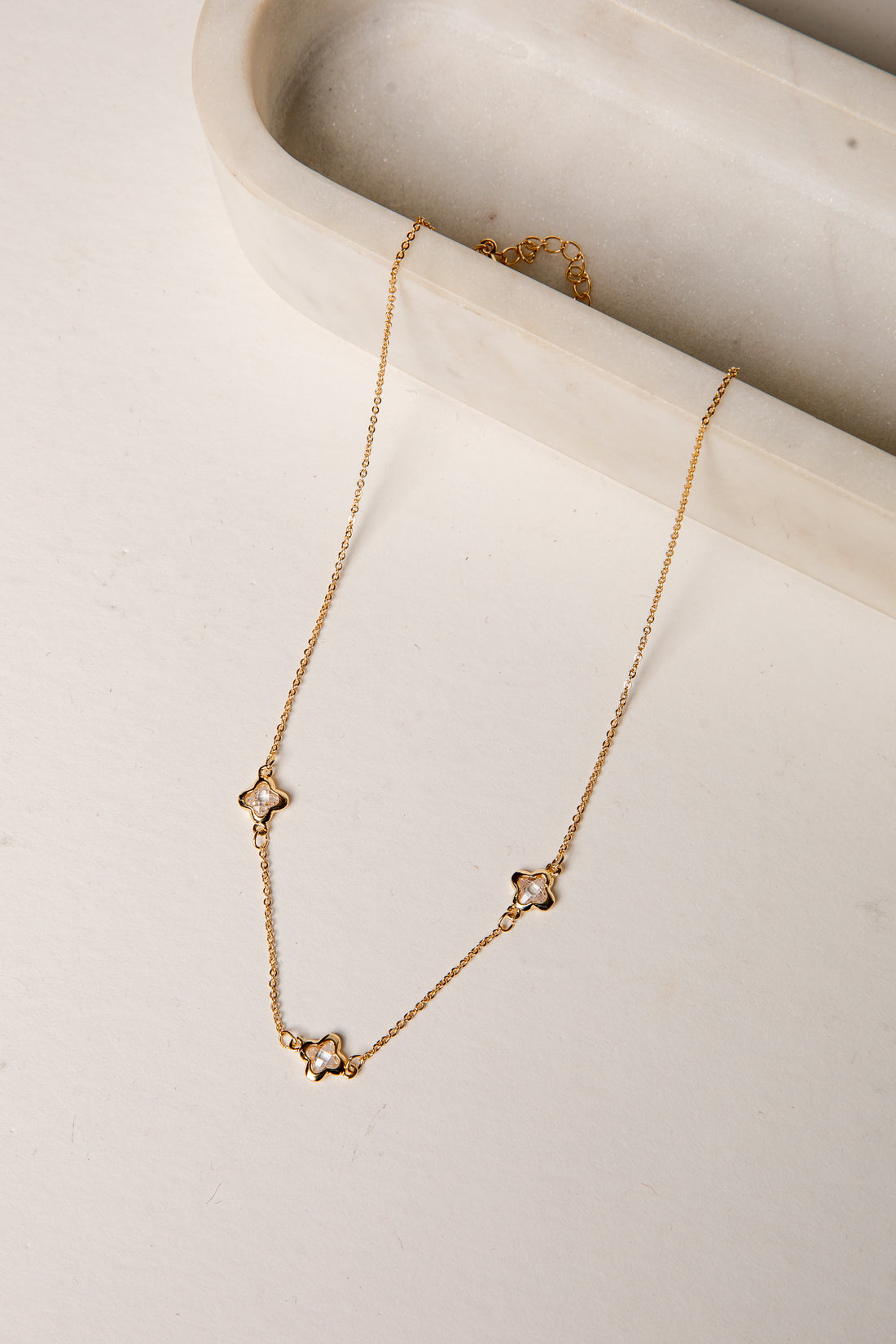 Gold necklace with star-shaped pendants on a marble surface
