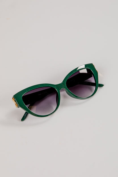 Green sunglasses with dark lenses on a light gray background