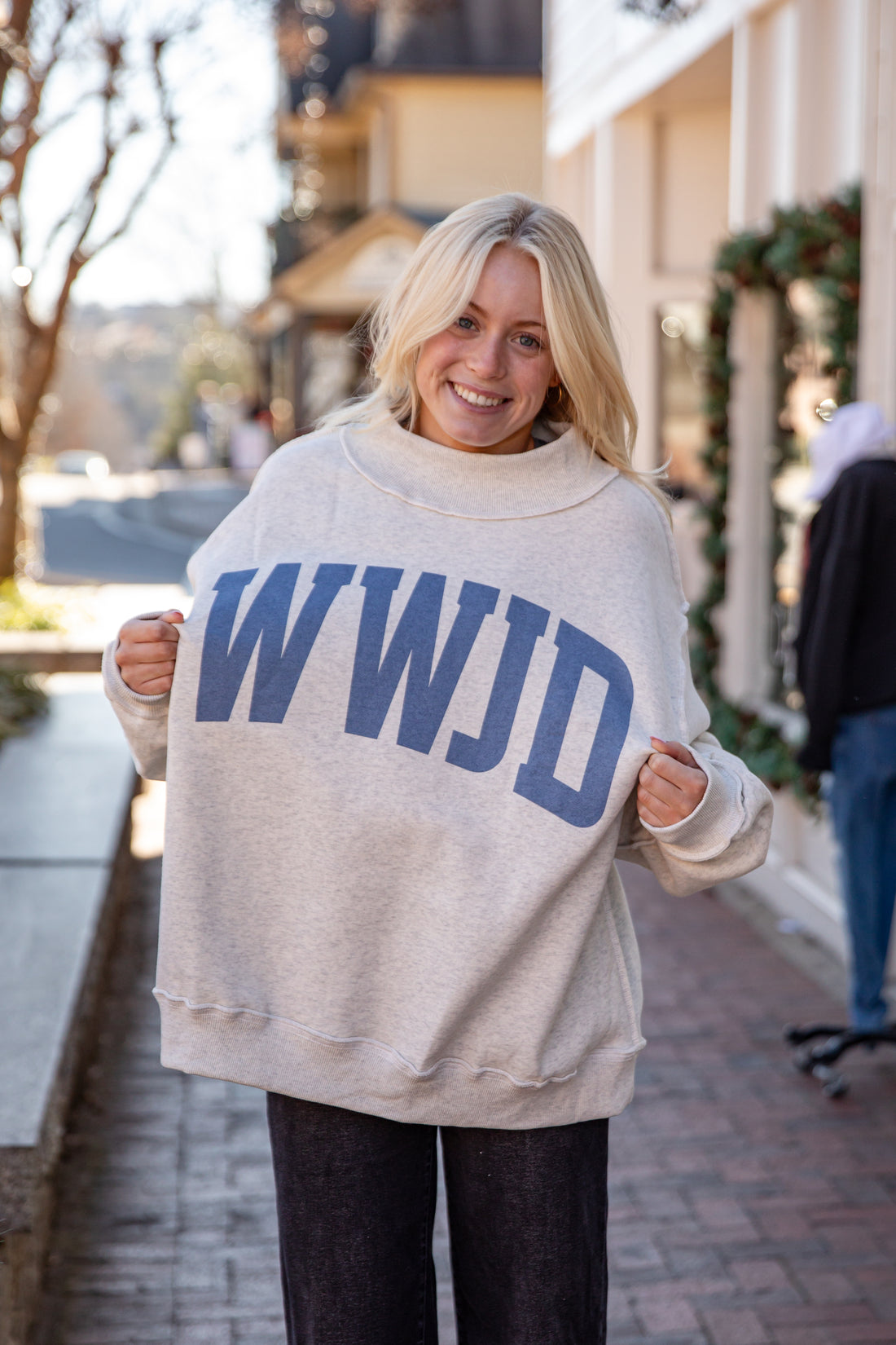 Woman wearing a beige sweatshirt with &