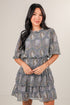Woman wearing a patterned dress against a plain background