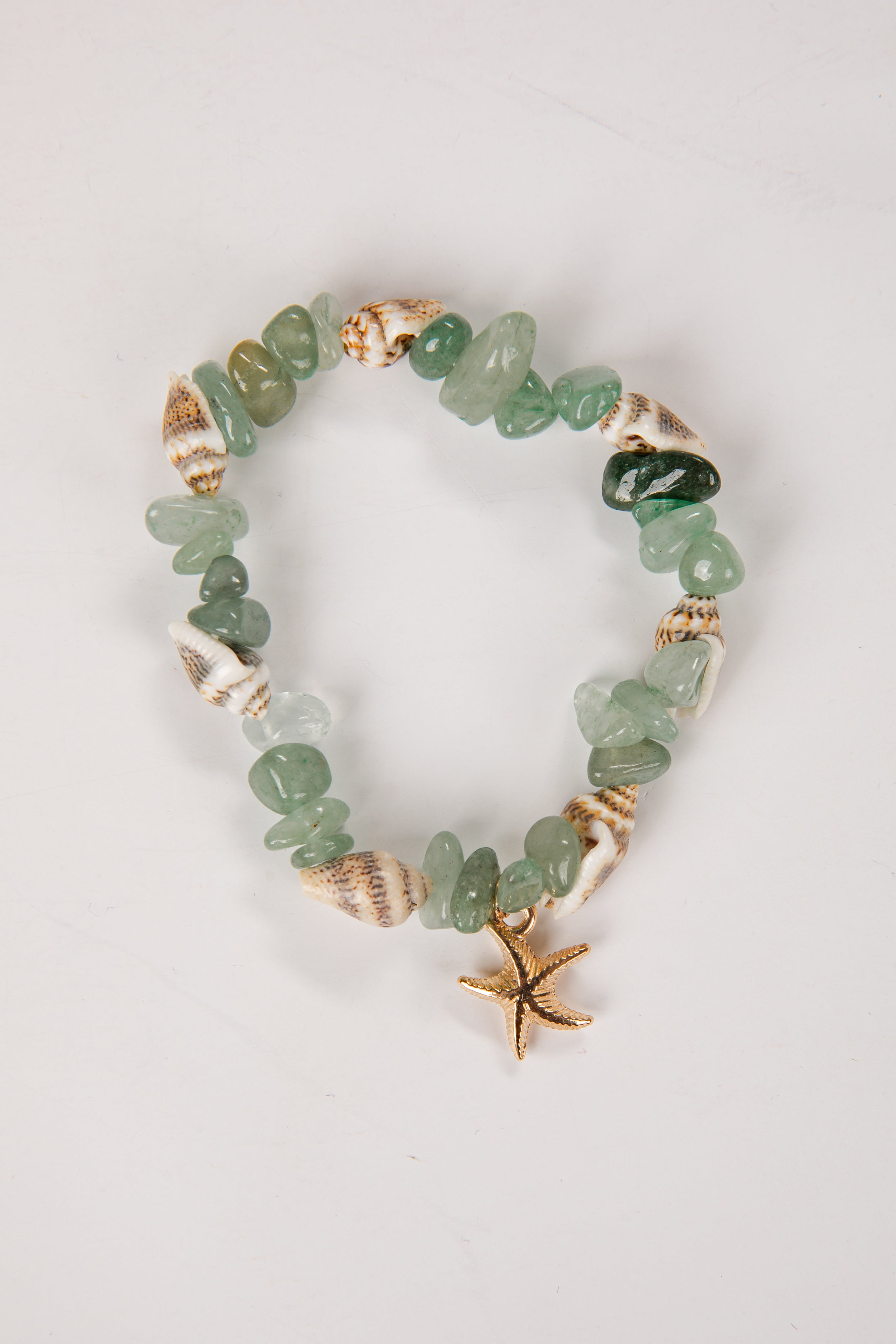 Green beaded bracelet with gold accents and starfish charm on a light gray background