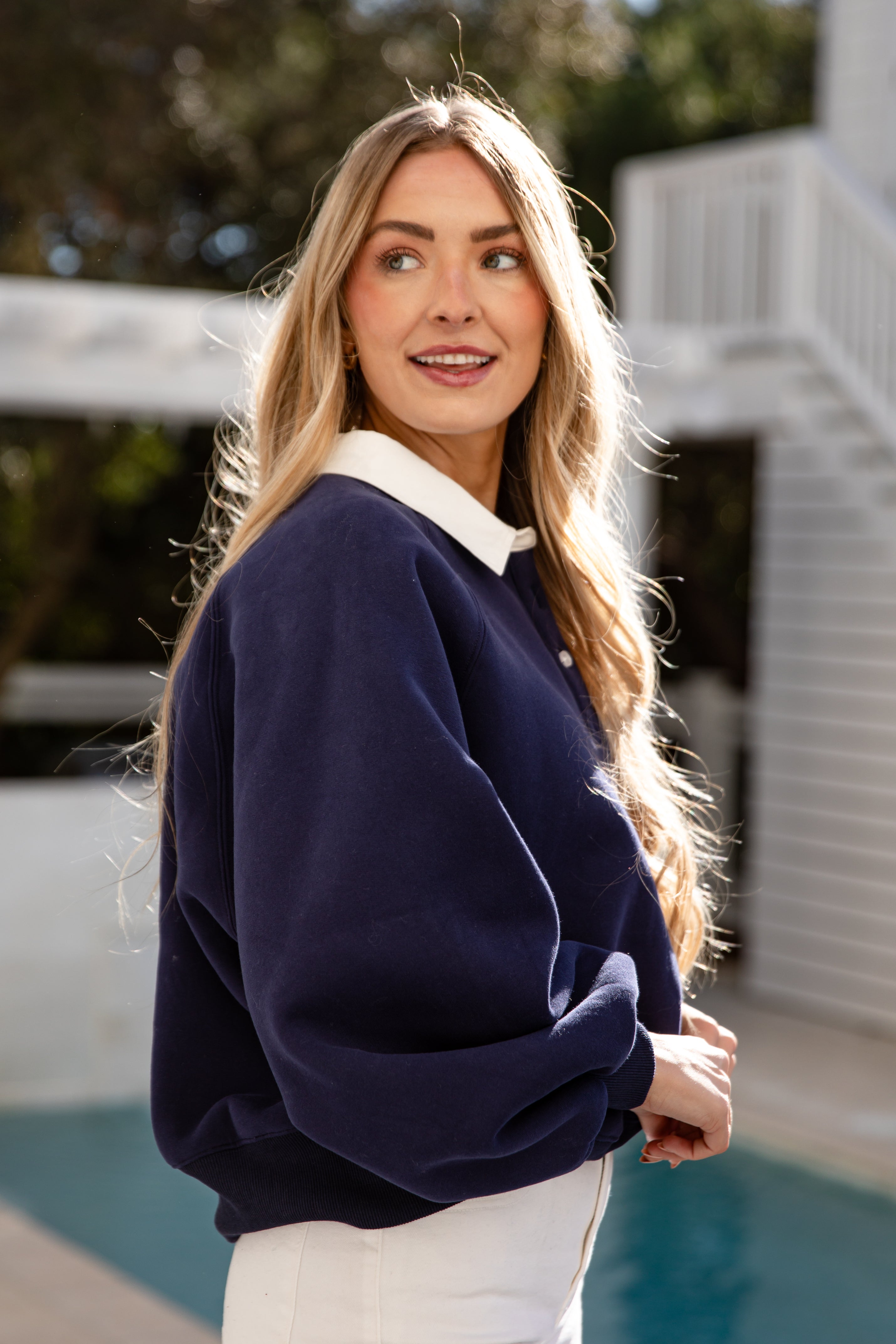 Woman wearing a navy sweater with a white collar outdoors