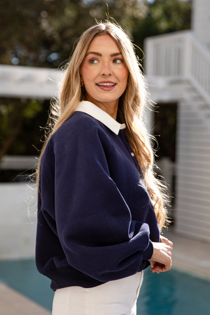 Woman wearing a navy sweater with a white collar outdoors