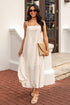 Woman in a white dress standing on a brick patio with a white building in the background