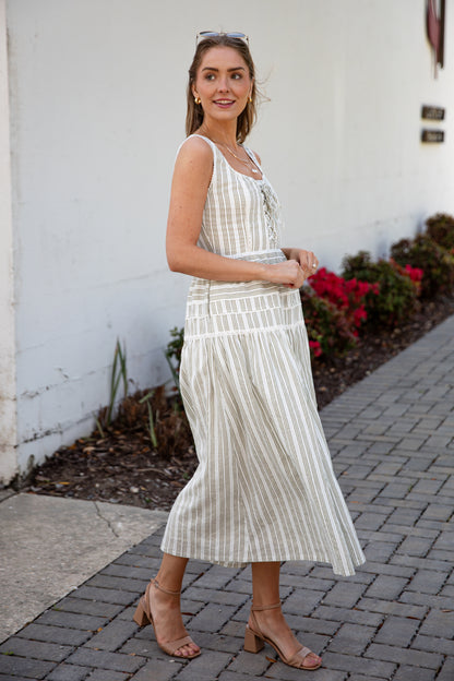 Woman wearing a spring striped maxi dress with sunglasses and nude heels