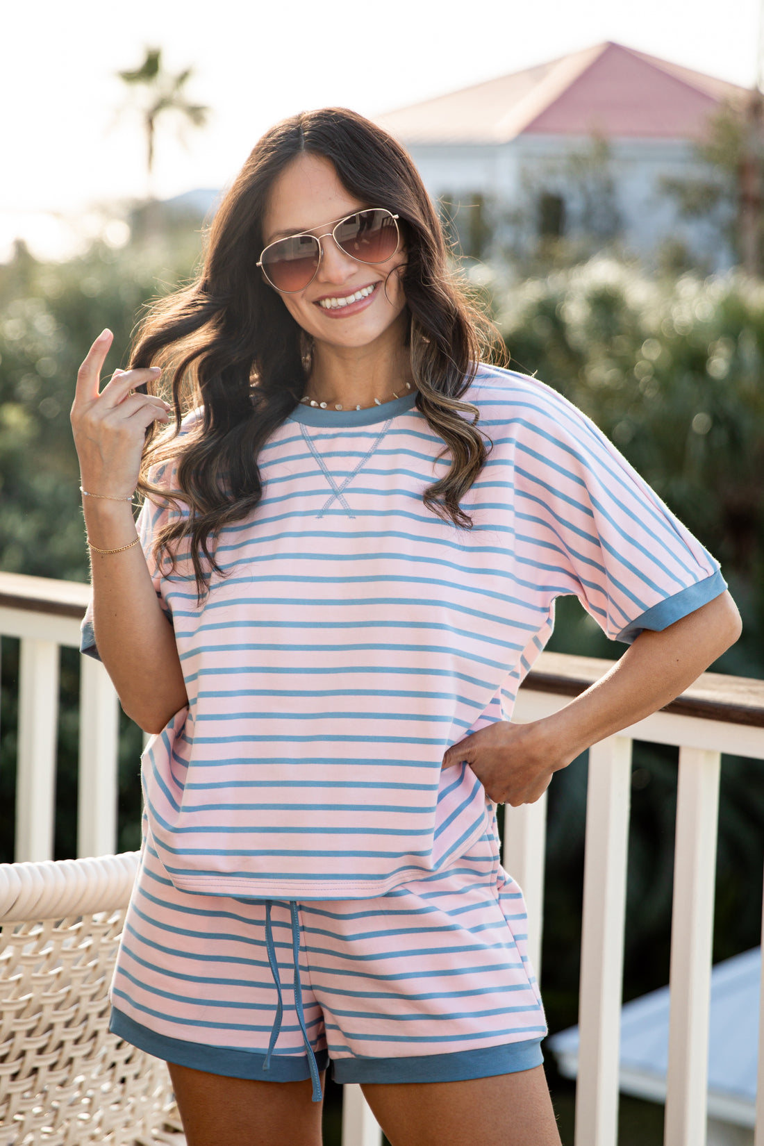 Woman wearing a striped outfit on a balcony with a blurred background