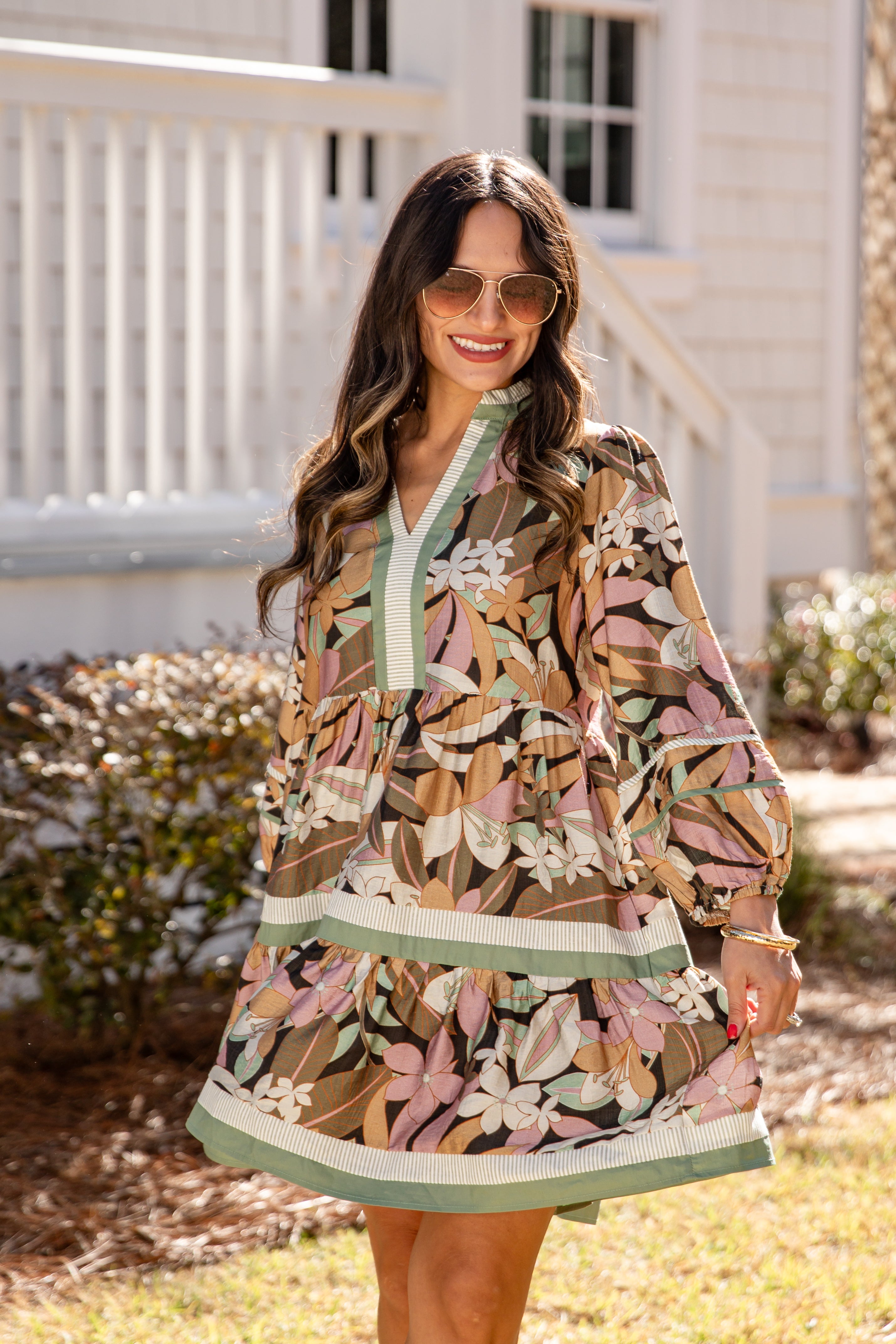 Woman wearing a floral dress standing in front of a house.