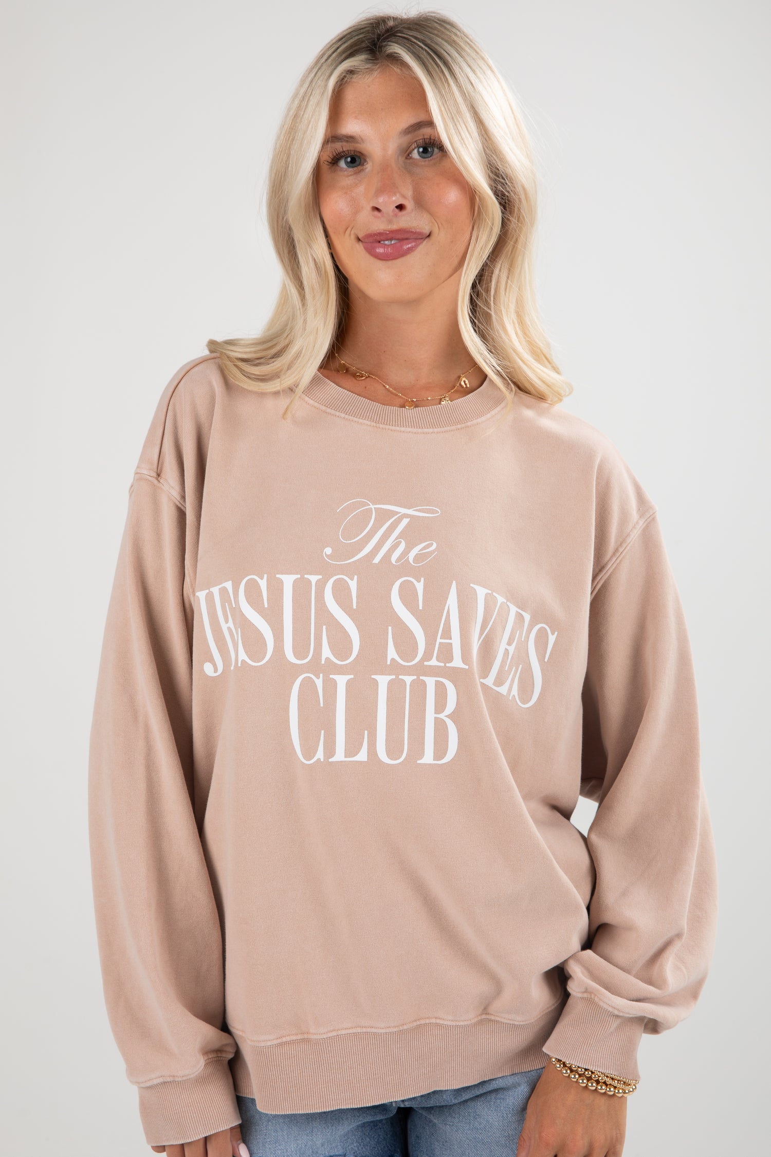 Woman wearing a beige sweatshirt with &