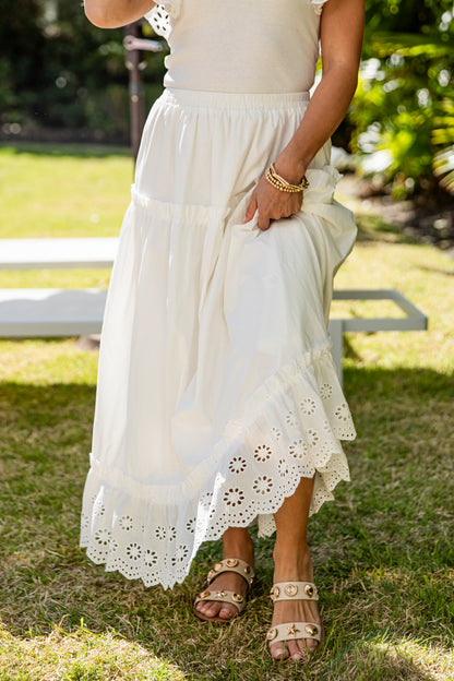 Person wearing a white dress with lace details on a grassy outdoor setting