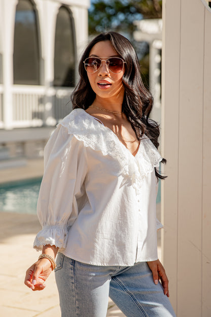Woman wearing a white blouse and sunglasses outdoors