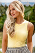 Woman wearing a yellow sleeveless top and striped pants outdoors
